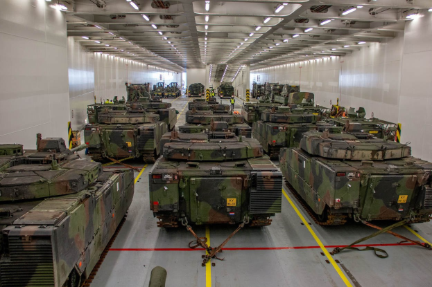 Eine gro├če Militargrundstuckhalle mit zahlreichen Panzern in einer ordentlichen Reihe, flankiert von Wanden und beleuchtet von Deckenleuchten.