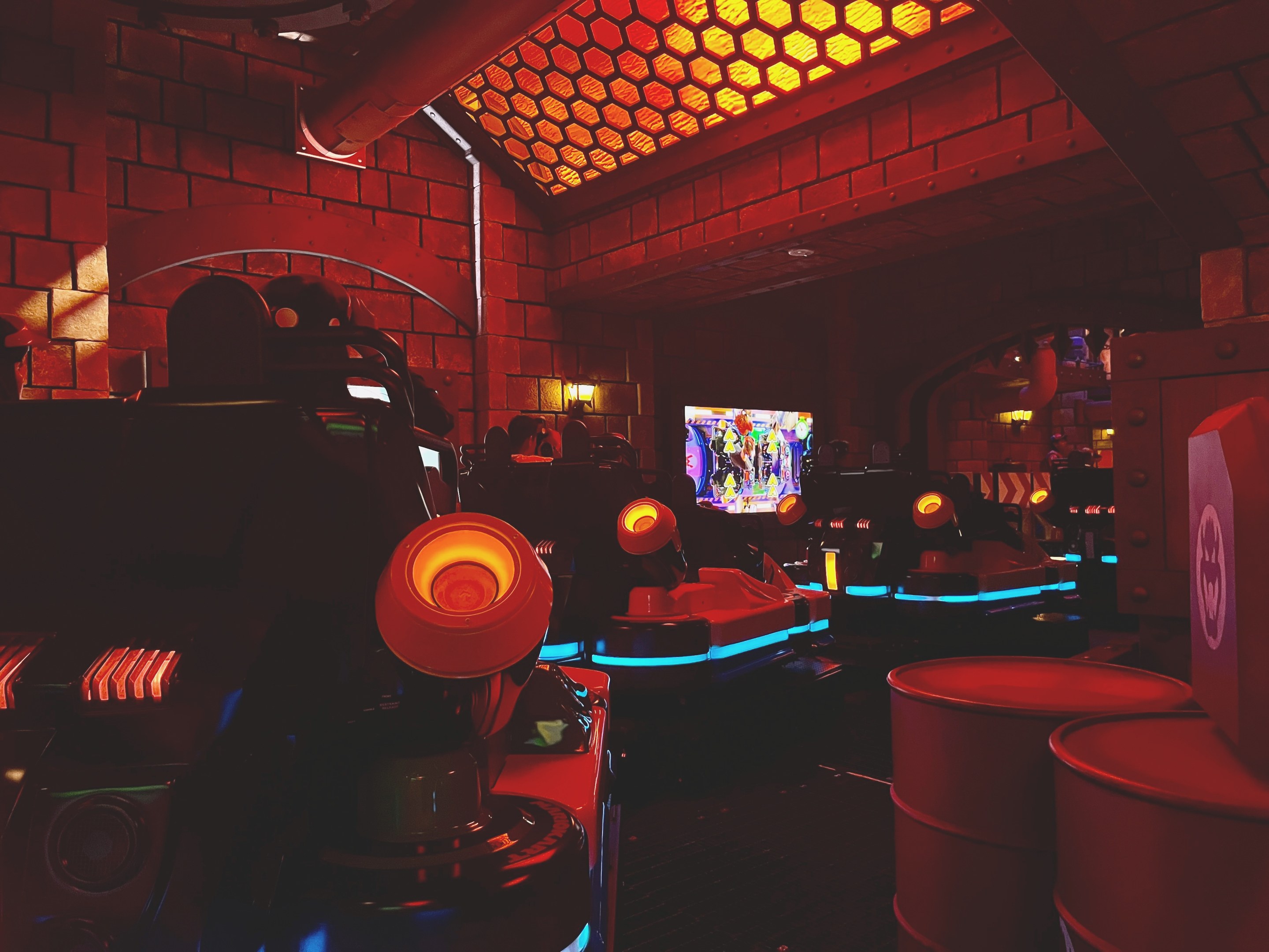 Ein hell erleuchteter Raum voller verschiedener Arcade-Videospielautomaten und -geräte, einschließlich Bildschirme, Lampen und Rohre.