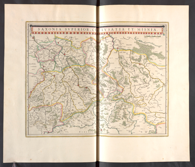 Ein aufgeschlagenes Buch mit einer detaillierten Karte von Sachsen, das verschiedene Provinzen und Städte hervorhebt, vor einem schwarzen Hintergrund.