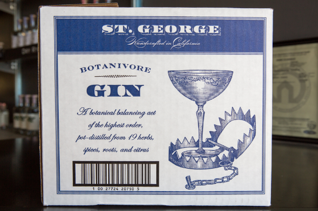 Ein Plakat mit Text steht vor Regalen voller vielen Flaschen.