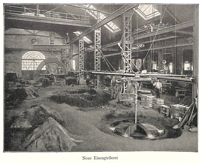 Schwarzes und weißes Foto einer frühen deutschen Fabrik mit Arbeitern, die Maschinen bedienen, umgeben von Metallstangen und -pfählen, beschriftet mit 'Neue Eisenglebeerei, die erste Fabrik in Deutschland' unten.