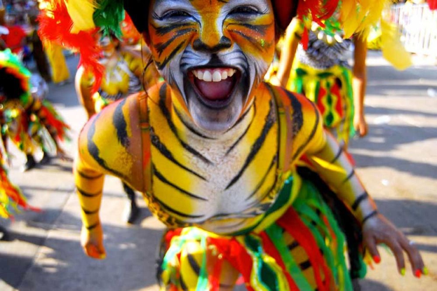 Eine Gruppe von Menschen in bunten Kostümen und Schminke auf einem Karneval, mit einer Frau in einem Tigerkostüm im Vordergrund.