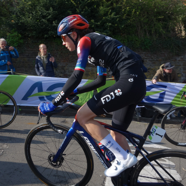 Eine Frau mit einem schwarzen Helm fährt ein Fahrrad auf einer Straße.
